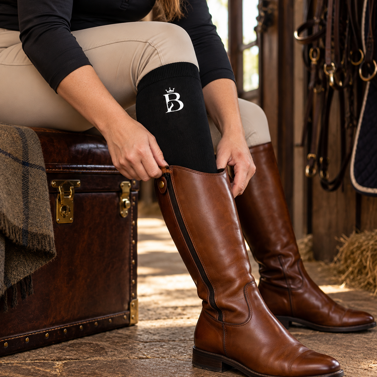Bajolek black tall-boot riding sock shown while putting on a cognac riding boot